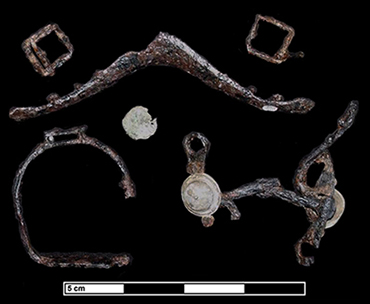 Figure 4: An assemblage of artifacts found together in a passageway at the Addison Plantation (18ST175). The iron buckles, saddle tree bracket, brass saddle nail, nearly complete curb bit, and small stirrup represent a side saddle left in place when the house was destroyed by fire ca. 1730.